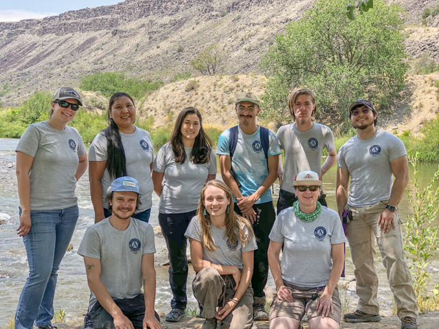 AmeriCorps New Mexico program DreamTree members pose and smile in front of a river wearing AmeriCorps branded shirts.